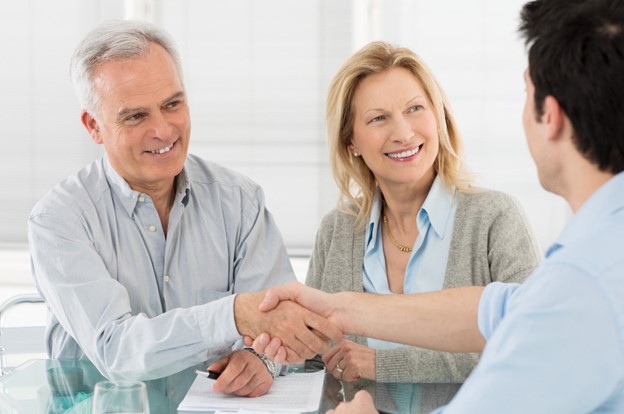 Smiling couple shaking hands with advisor